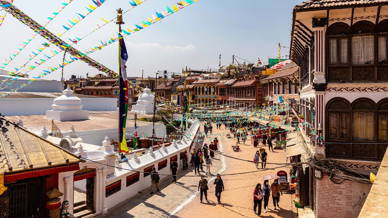 Boudhanath Stupa square with prayer flags and street life, Kathmandu